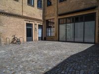 the sidewalk is paved with stones and has a bench in front of it, with no people inside