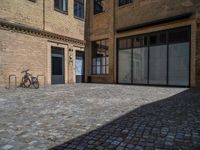 the sidewalk is paved with stones and has a bench in front of it, with no people inside