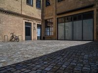 the sidewalk is paved with stones and has a bench in front of it, with no people inside