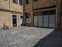 the sidewalk is paved with stones and has a bench in front of it, with no people inside