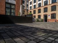 a sidewalk with chairs next to the brick building on the side, some have stairs and some buildings in the background