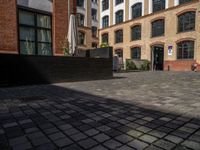 a sidewalk with chairs next to the brick building on the side, some have stairs and some buildings in the background