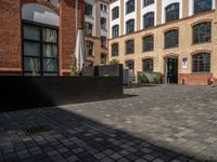 a sidewalk with chairs next to the brick building on the side, some have stairs and some buildings in the background