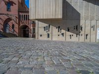 cobblestone driveway surrounded by modern buildings on sunny day with sun reflecting onto the windows