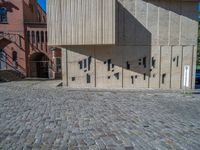 cobblestone driveway surrounded by modern buildings on sunny day with sun reflecting onto the windows