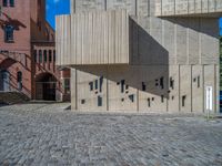 cobblestone driveway surrounded by modern buildings on sunny day with sun reflecting onto the windows