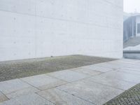 a concrete wall near the road is very large and empty, the wall has some holes in it