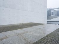 a concrete wall near the road is very large and empty, the wall has some holes in it