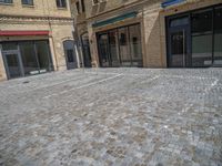 the sidewalk is paved with stones and has a bench in front of it, with no people inside