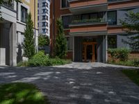 a residential driveway with a bench and bushes in between buildings and green grass on either side