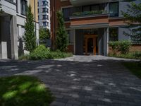 a residential driveway with a bench and bushes in between buildings and green grass on either side