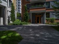 a residential driveway with a bench and bushes in between buildings and green grass on either side