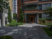 a residential driveway with a bench and bushes in between buildings and green grass on either side