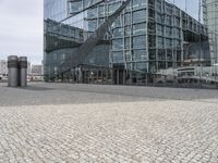 a glass office building has curved windows and an intricate staircase outside the entrance of the building