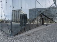 reflection in the glass wall of a building with buildings behind it near another glass wall