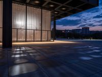 a windowed area with large glass walls, lights, and dark concrete flooring