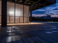 a windowed area with large glass walls, lights, and dark concrete flooring