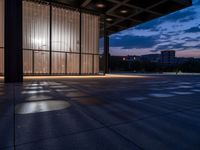 a windowed area with large glass walls, lights, and dark concrete flooring