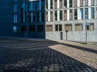 a building with several windows on the side of it and an empty street corner on the ground