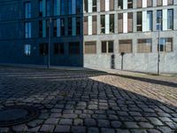 a building with several windows on the side of it and an empty street corner on the ground