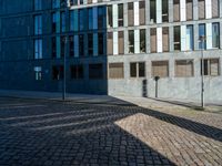 a building with several windows on the side of it and an empty street corner on the ground