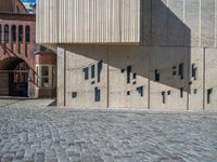 cobblestone driveway surrounded by modern buildings on sunny day with sun reflecting onto the windows