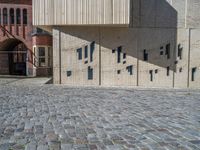 cobblestone driveway surrounded by modern buildings on sunny day with sun reflecting onto the windows