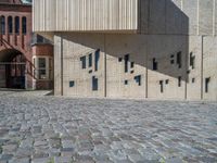 cobblestone driveway surrounded by modern buildings on sunny day with sun reflecting onto the windows