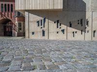 cobblestone driveway surrounded by modern buildings on sunny day with sun reflecting onto the windows