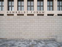 the entrance to the humboldt forum building is tiled with brickwork and a clock tower in the background