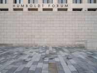 the entrance to the humboldt forum building is tiled with brickwork and a clock tower in the background