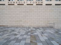 the entrance to the humboldt forum building is tiled with brickwork and a clock tower in the background