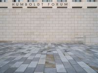 the entrance to the humboldt forum building is tiled with brickwork and a clock tower in the background