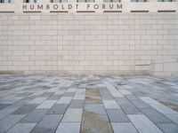 the entrance to the humboldt forum building is tiled with brickwork and a clock tower in the background