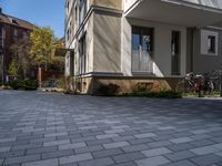 a driveway with an attached walkway and two bikes parked along it on the sidewalk behind a multi - story house