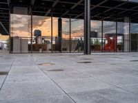 a fire hydrant sitting in front of a glass building under a sunset sky outside