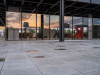 a fire hydrant sitting in front of a glass building under a sunset sky outside