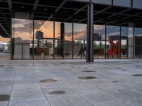 a fire hydrant sitting in front of a glass building under a sunset sky outside