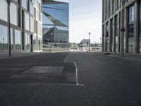 an empty city street with some buildings and clouds in the background in this image, a blue building is reflected in the glass