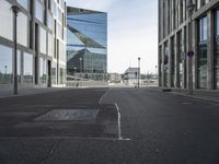 an empty city street with some buildings and clouds in the background in this image, a blue building is reflected in the glass