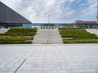 a view of the back steps of a building with shrubs on both sides and two fountains in the background