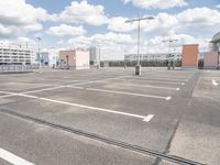 an empty parking lot in a parking lot with two buildings behind it and sky with clouds