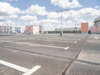 an empty parking lot in a parking lot with two buildings behind it and sky with clouds