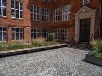 several plants sit in decorative concrete planters along the sidewalk of a building that is very modern