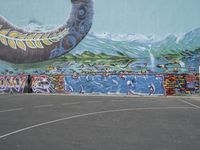 the painted elephant is near a basketball court with a man standing outside of it's door