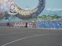 the painted elephant is near a basketball court with a man standing outside of it's door