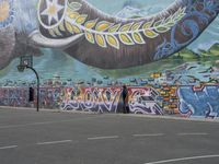 the painted elephant is near a basketball court with a man standing outside of it's door