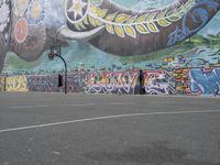 the painted elephant is near a basketball court with a man standing outside of it's door