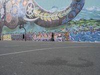 the painted elephant is near a basketball court with a man standing outside of it's door