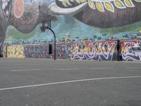 the painted elephant is near a basketball court with a man standing outside of it's door